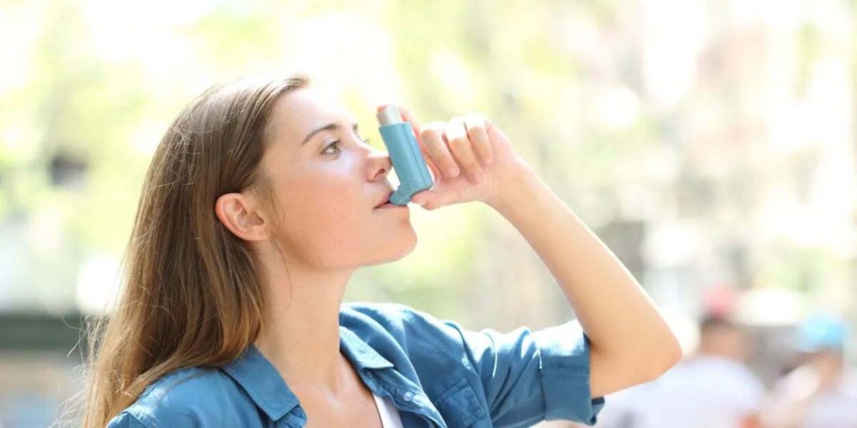 side view portrait of an asthmatic woman using a inhaler outdoors in the street