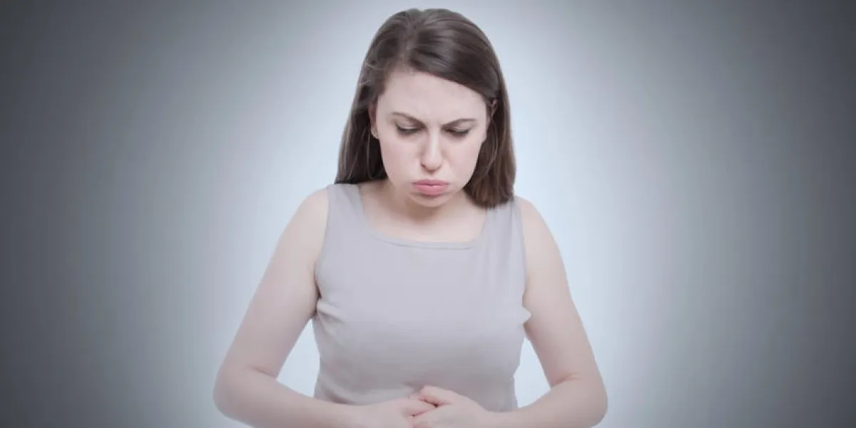 portrait, jeune femme, placer, mains, sur, estomac, avoir, mal courbatures, douleur, isolé, sur, gris, mur, fond négatif, émotion, expression faciale, réaction, problèmes santé, problèmes