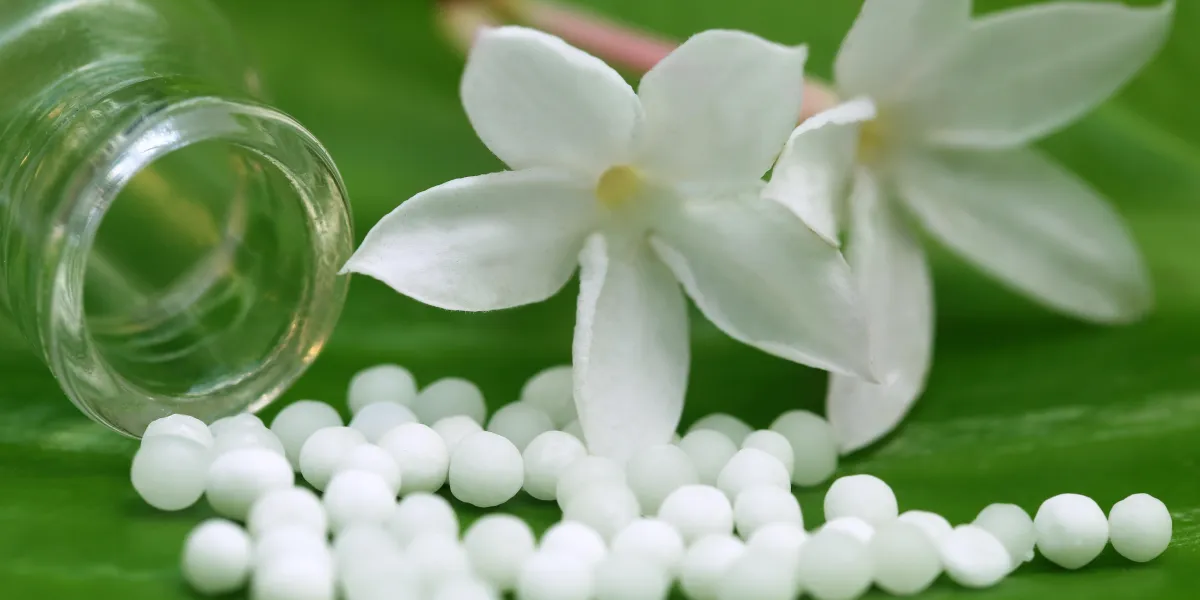 homeopathy globules with herbal flower on green leaf