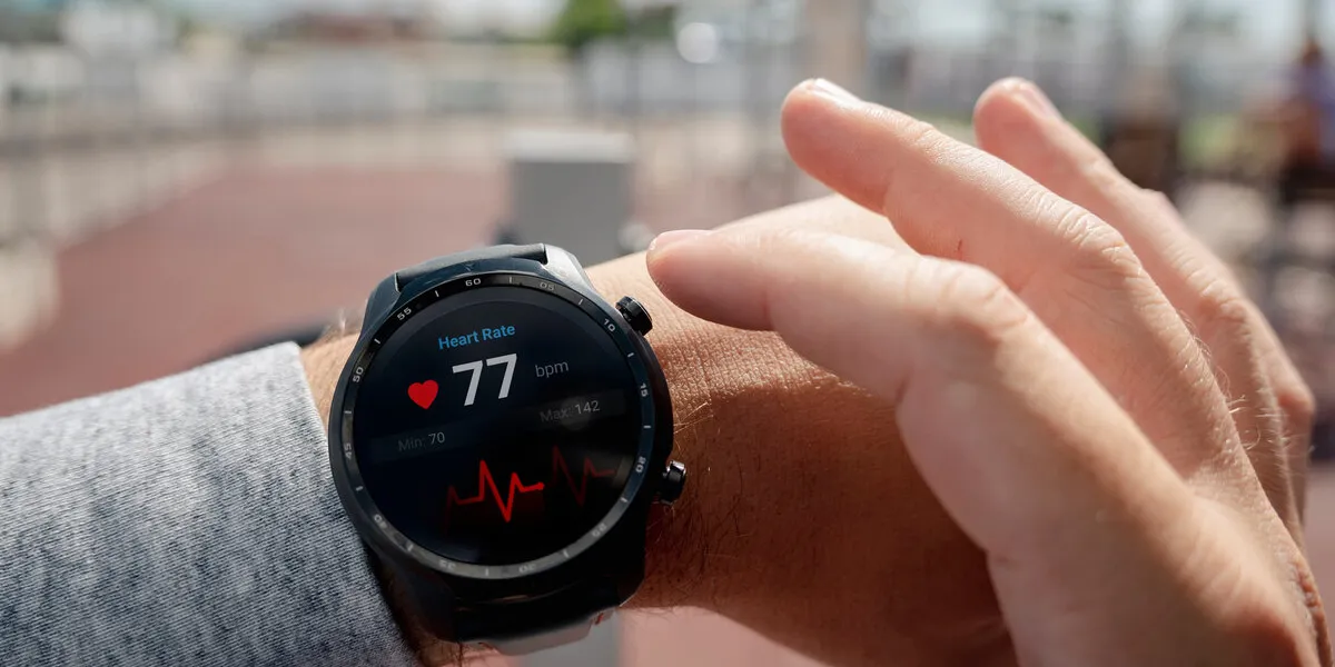 close-up of smart watch health tracker with the heart rate shown on the screen modern stylish and innovation wearable device athlete checks his heart rate before training at the stadium heart beat