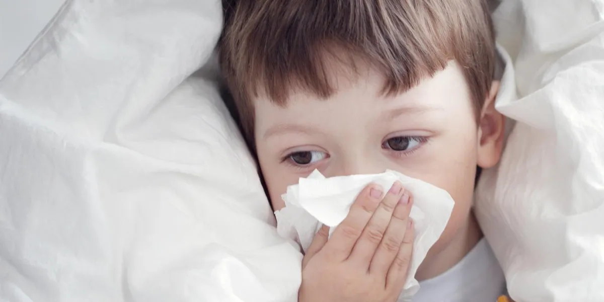garçon s'essuie le nez avec un mouchoir