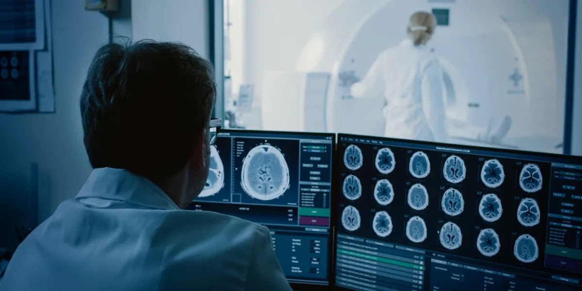in medical laboratory patient undergoes mri or ct scan process under supervision of radiologist, in control room doctor watches procedure and monitors with brain scans results