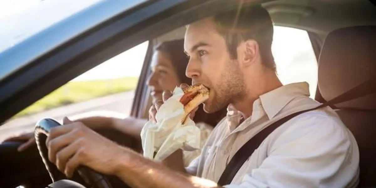 couple dans la voiture - l'homme conduit et mange baguette
