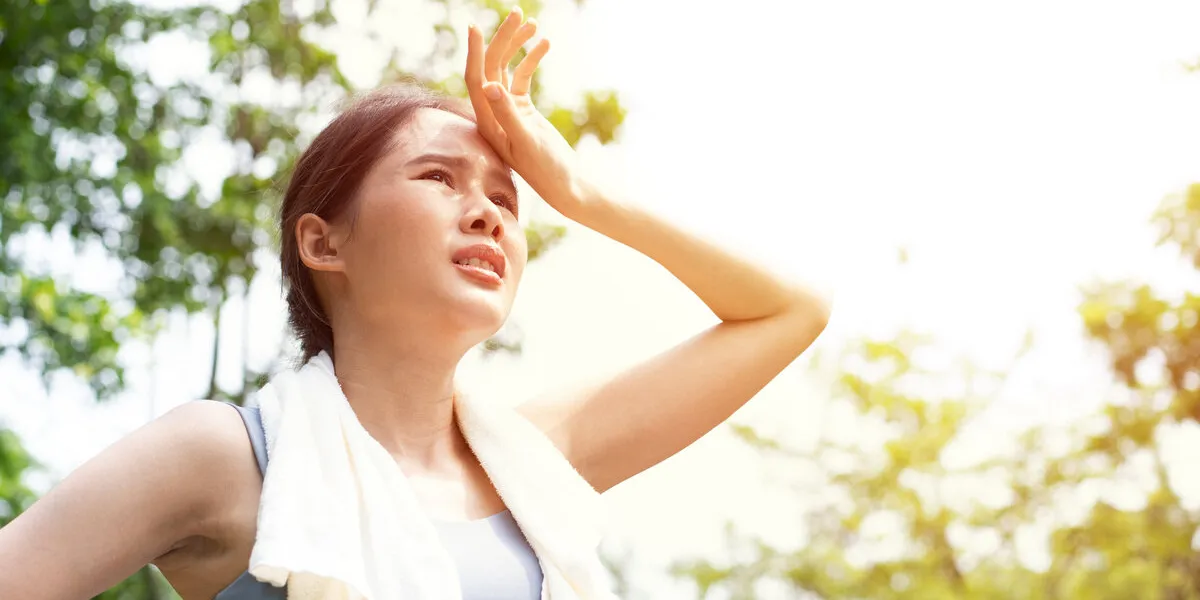 sport asian woman gets tired and get dizzy, feel bad pain and suffer from heat stroke outdoors when jogging or exercise outdoor with strong sunlight in summer season heatstroke and heat wave concept