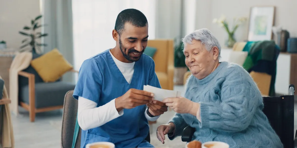 nursing home, photo album and caregiver with old woman in retirement, break and bonding together love, memory or senior person with pictures for support or nostalgia with care, nurse or conversation