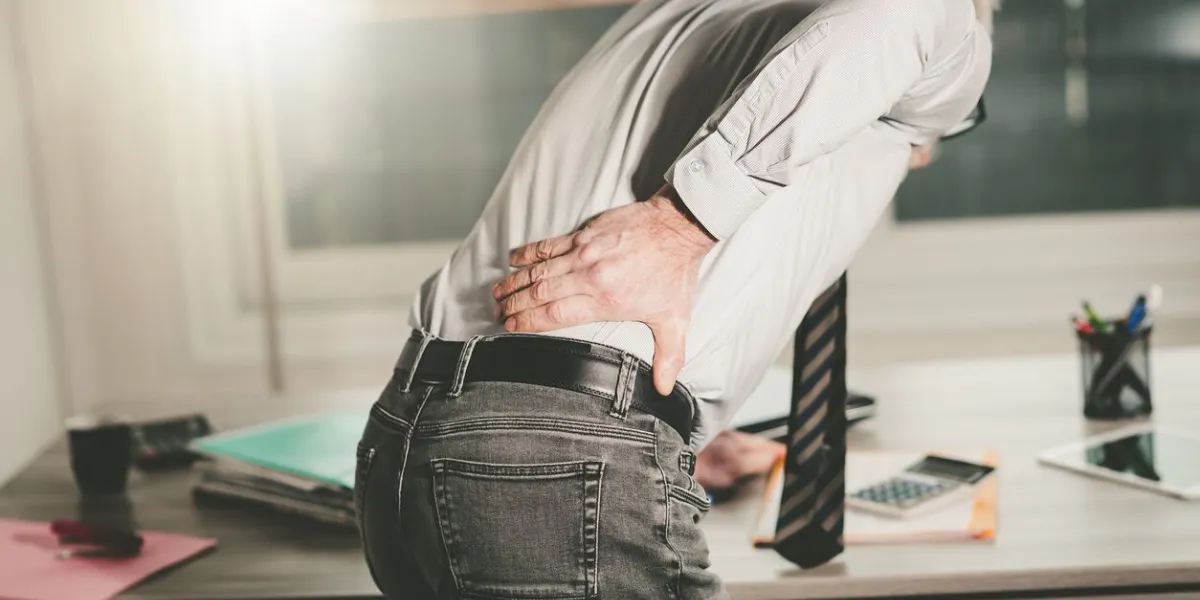 businessman suffering from back pain in office, light effect