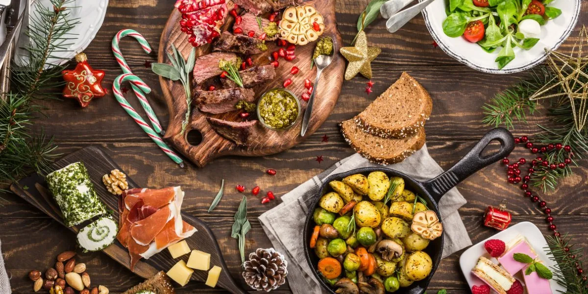 flat lay of delicious christmas themed dinner table with roasted meat steak, appetizers and desserts top view holiday concept