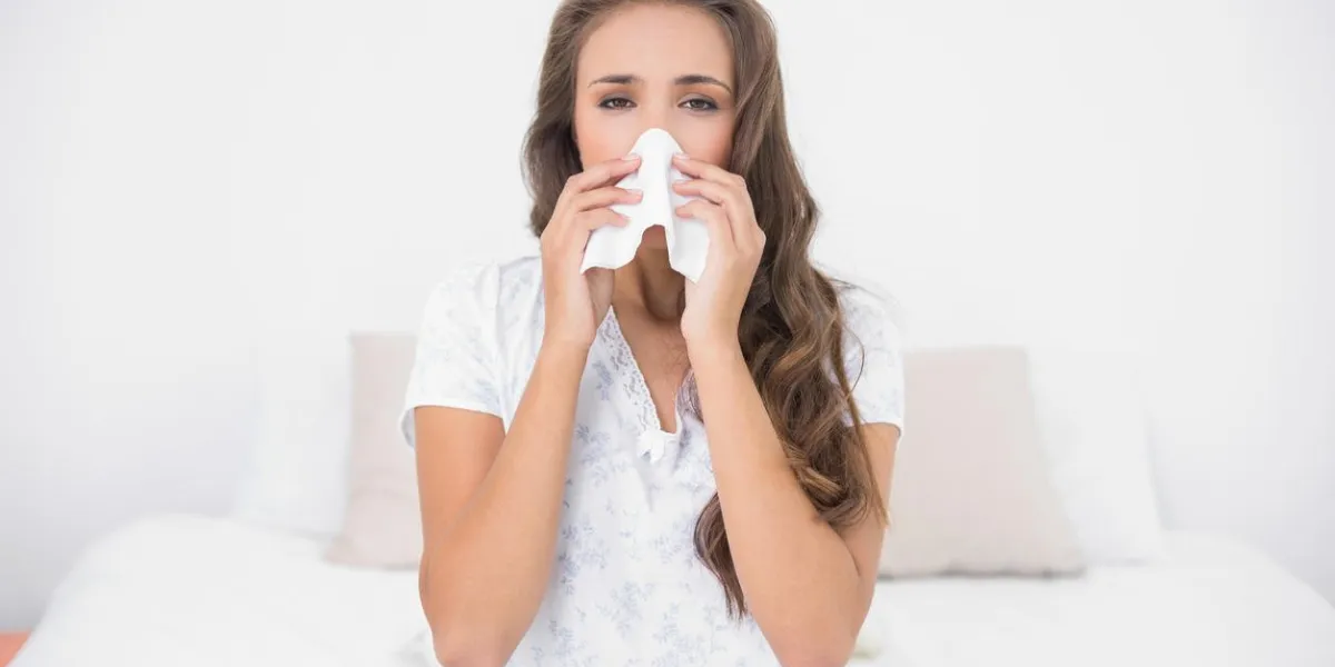 pretty brunette blowing her nose in bright bedroom