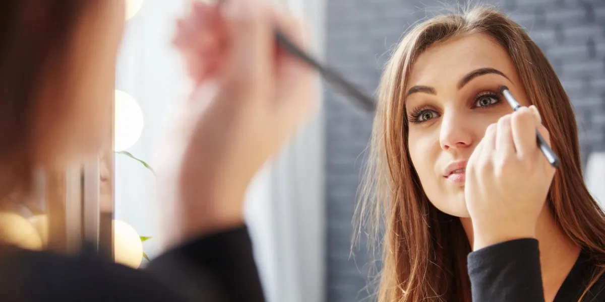 reflet dans le miroir de la belle dame appliquant fard à paupières