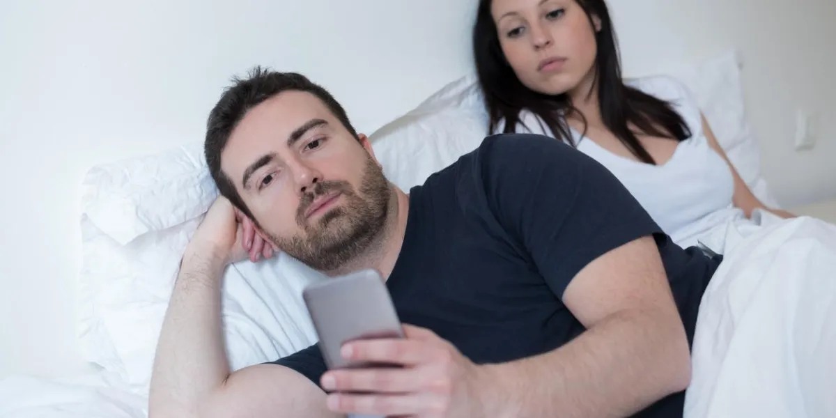 homme négligeant sa petite amie et utilisant son téléphone portable dans le lit
