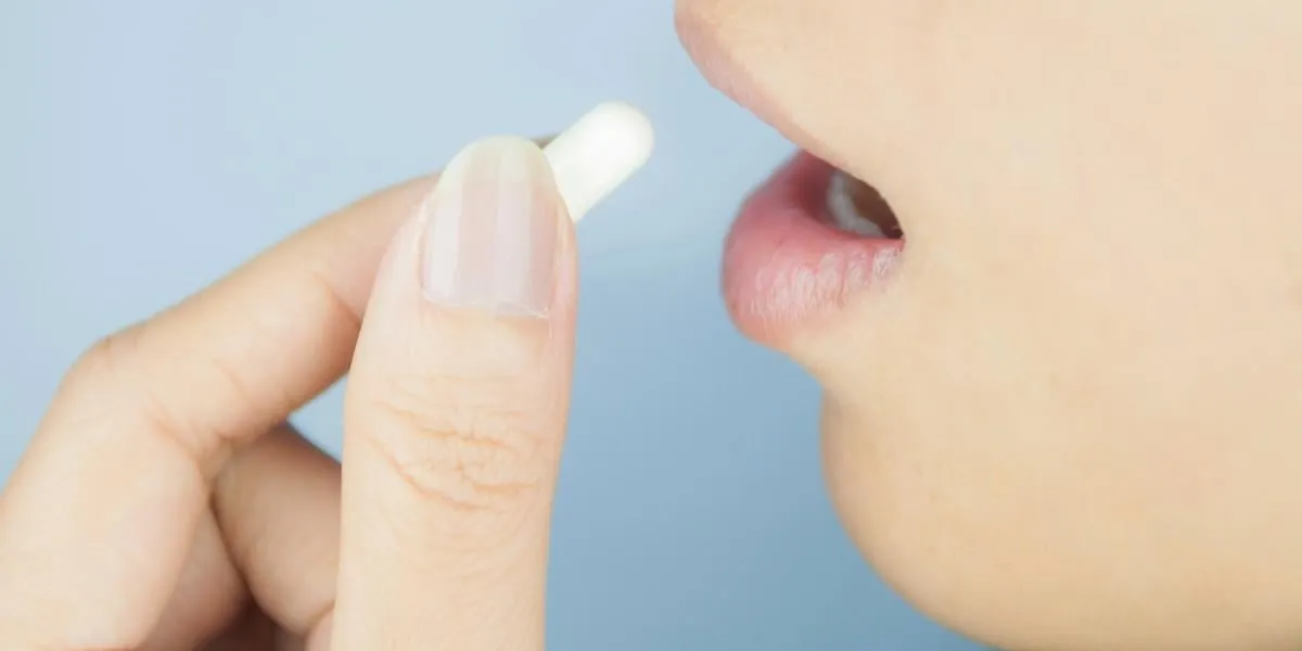 closed up white capsule into mouth