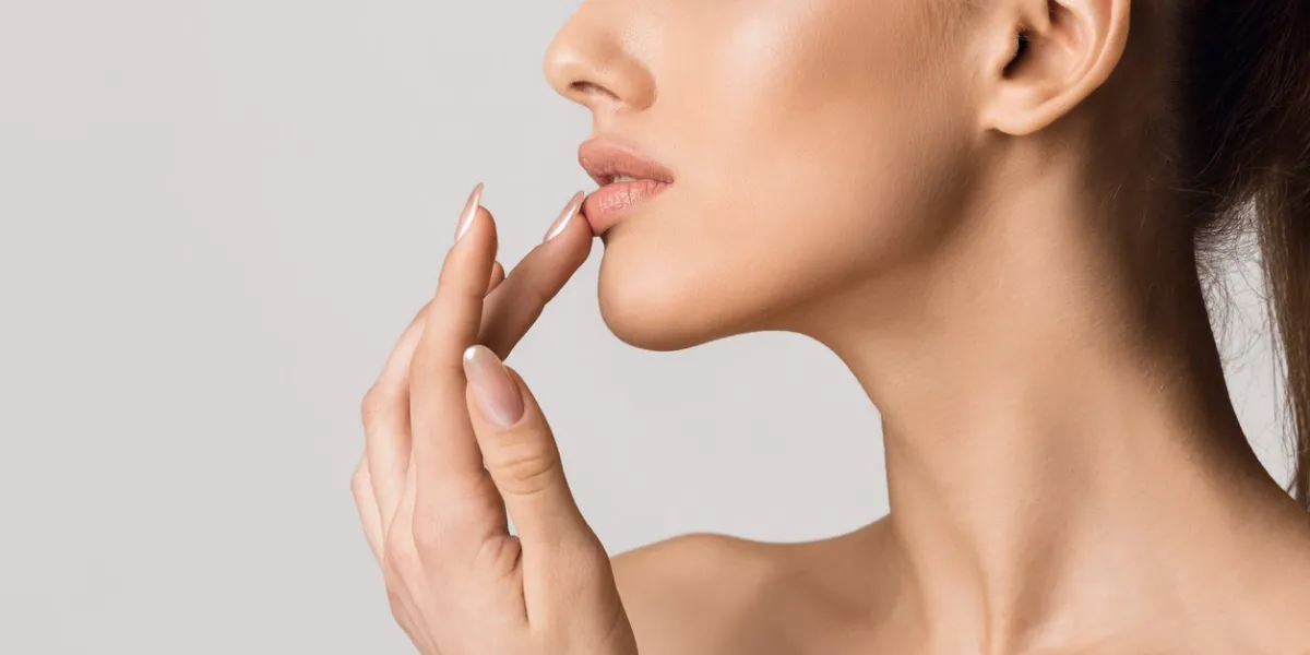 lip augmentation beautiful girl touching her lips over gray background, copy space