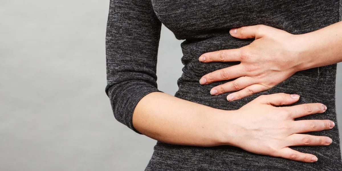 woman having strong stomach ache syndroms of indigestion pregnancy female suffer on belly pain, holds hands on abdomen, part of body on grey