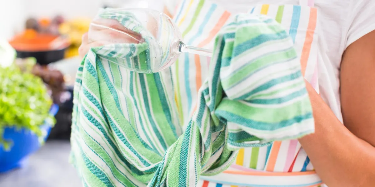 jeune femme polir un verre dans sa cuisine moderne