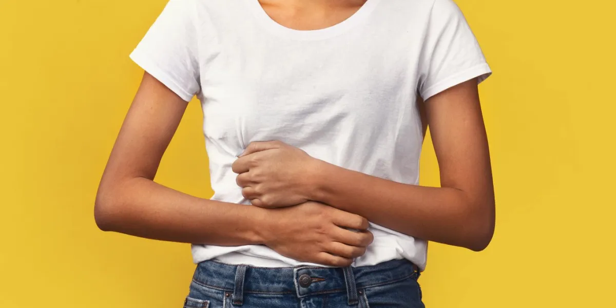 symptoms of food poisoning close-up of african girl holding hands on stomach suffering from abdominal pain