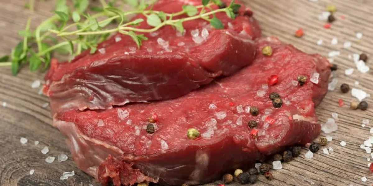 viande crue fraîche avec du sel, du poivre et des herbes sur la table en bois