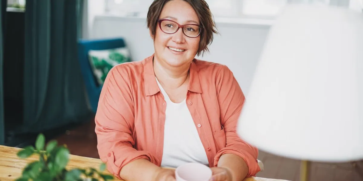 adult charming brunette woman in glasses plus size body positive with cup of tea at the home