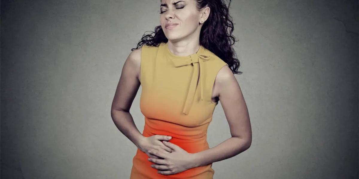 young woman with hands on stomach having bad aches pain isolated on gray background food poisoning, cramps negative emotion face expression health problems