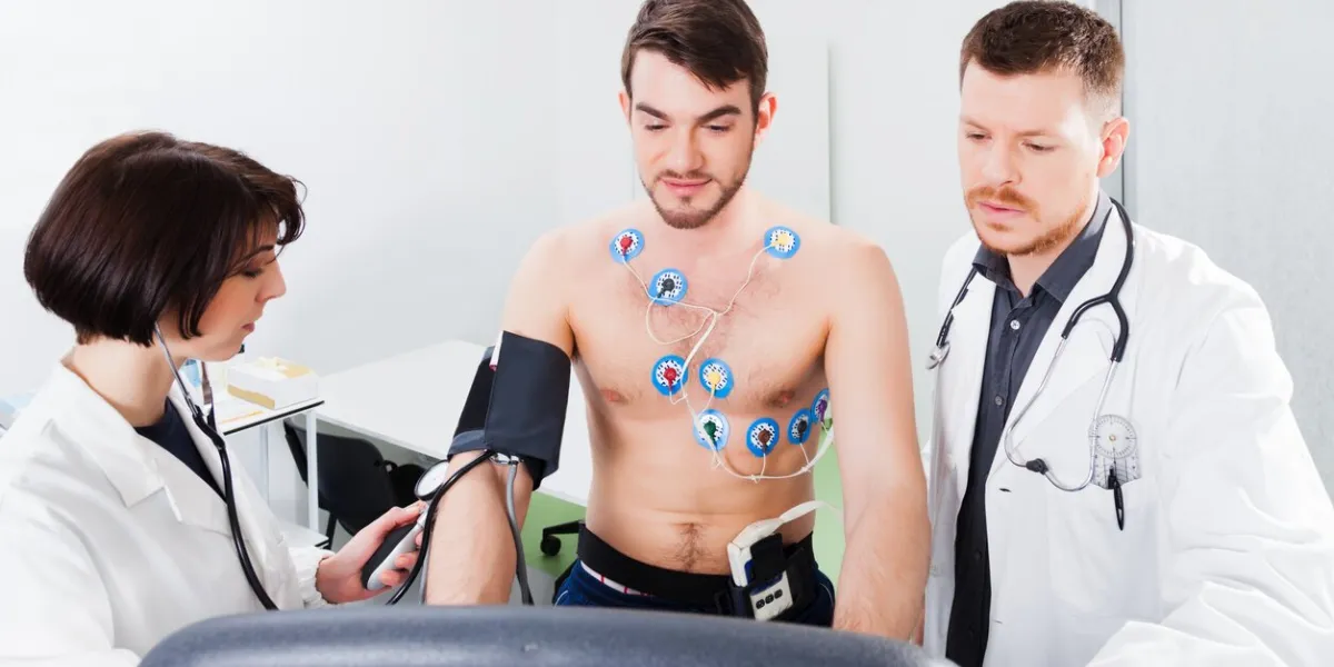 athlete does a cardiac stress test in a medical study, monitored by the doctor and nurse