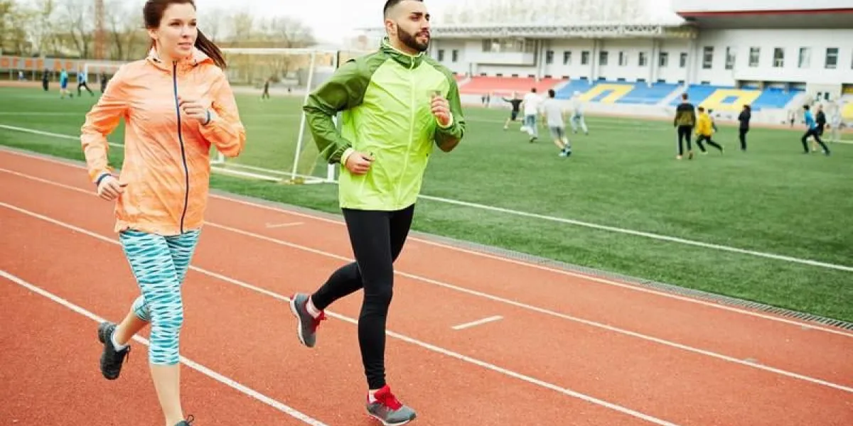 jeune couple actif en cours d'exécution sur le stade