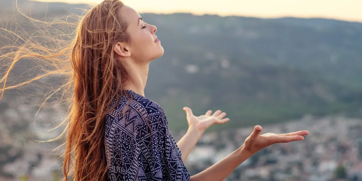 a young woman with her hands raised in worship and praise to god
