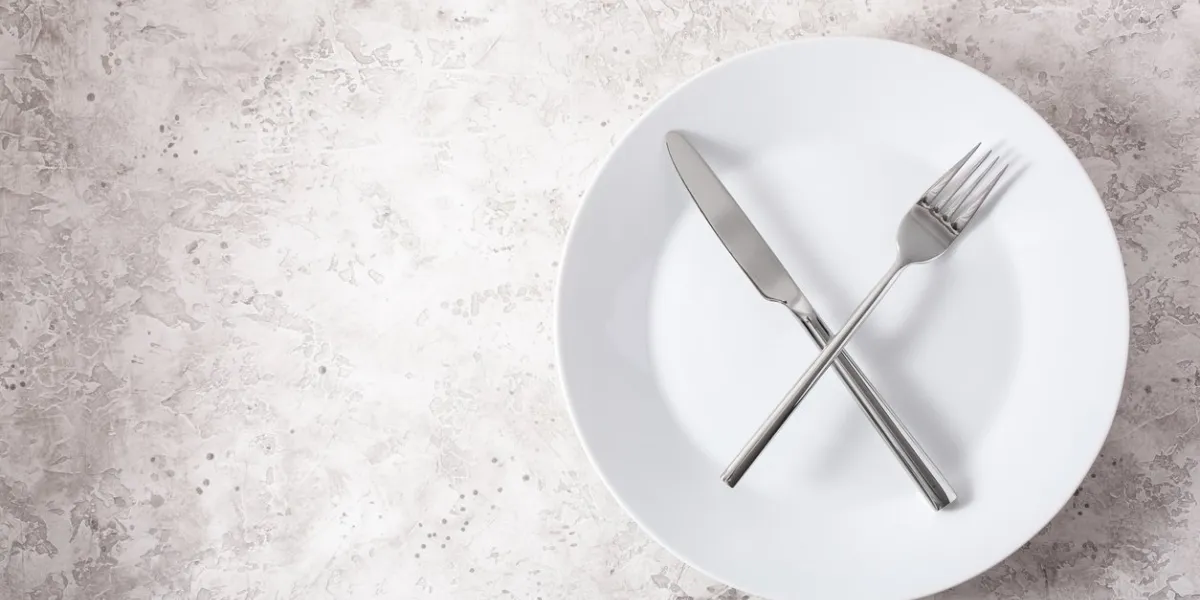 concept of intermittent fasting and ketogenic diet, weight loss fork and knife crossed on a plate