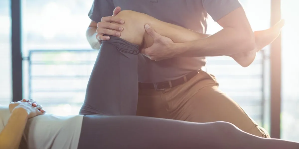 physiothérapeute donnant une thérapie au genou à une femme en clinique