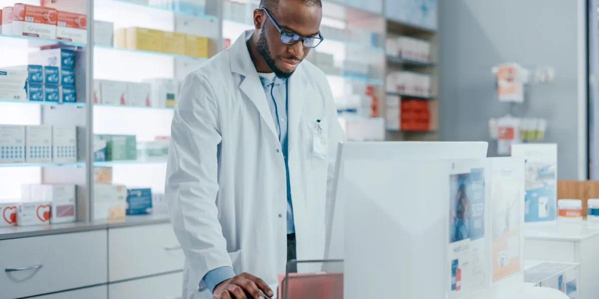 pharmacy drugstore checkout counter  portrait of professional black pharmacist working on computer, checks inventory of medicine, supply of supplements, health care and beauty products, vitamins