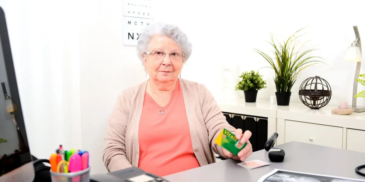 senior woman in doctor's office showing carte vitale medical french social security card