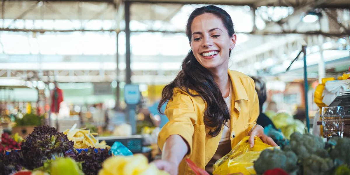 beautiful young woman buying vegetables young cheerful woman at the market raw food, veggie concept portrait of smiling good looking girl in casual clothing