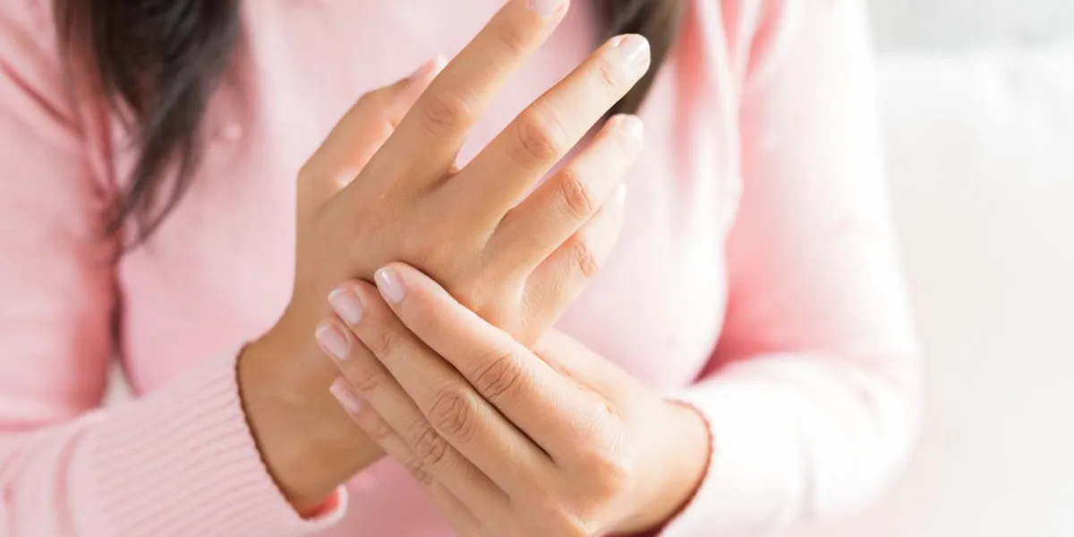 closeup woman sitting on sofa holds her wrist hand injury, feeling pain health care and medical concept