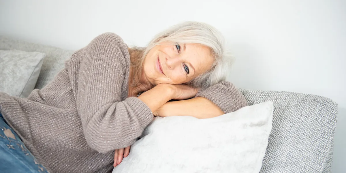 bellissima donna sopra i 50 anni che si rilassa sul divano con sguardo dolce e affettuoso