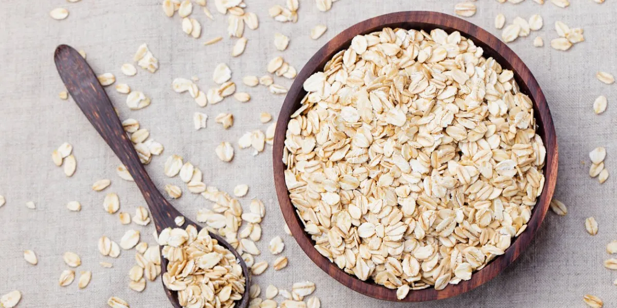 healthy breakfast organic oat flakes in a wooden bowl grey textile background top view copy space