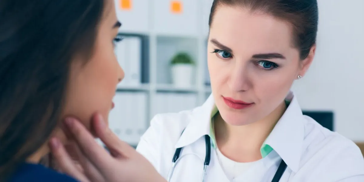 young female doctor palpating lymph nodes of a patient doctor touching the throat of a patient medical exam, clinic, hospital