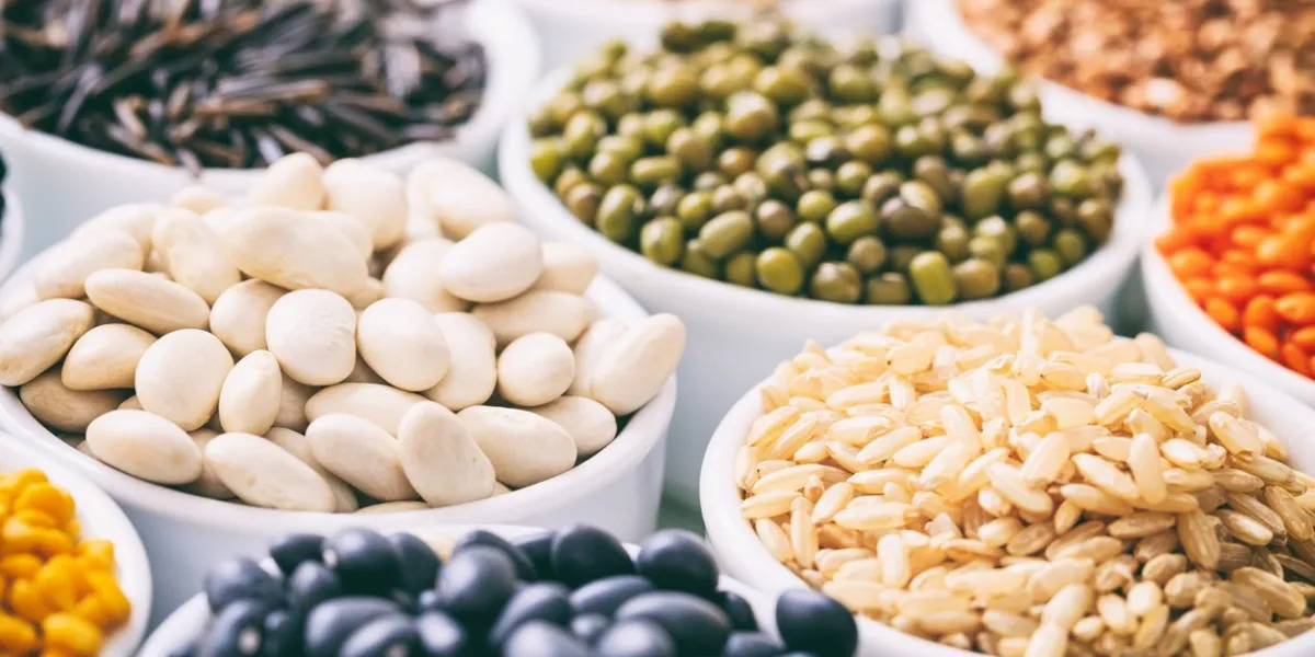 various raw legumes and rice in white bowls