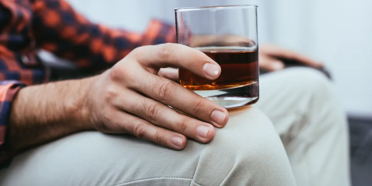 cropped shot of young man holding glass of whiskey