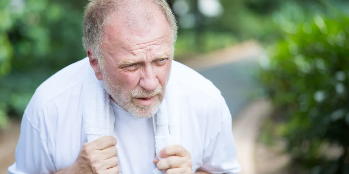 closeup portrait, senior guy holding towel, very tired, exhausted from over exertion, sun stroke, isolated outdoors outside green trees background