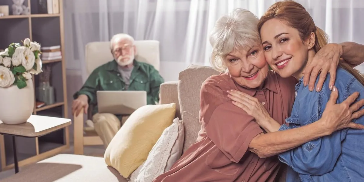 portrait of glad grandmother hugging smiling woman they looking at camera while sitting on sofa family concept