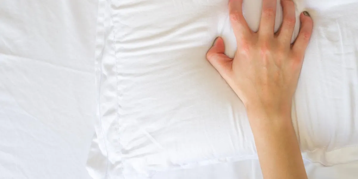 hand sign orgasm of woman on white bed , hand of female pulling white sheets in ecstasy , feeling and emotion concept