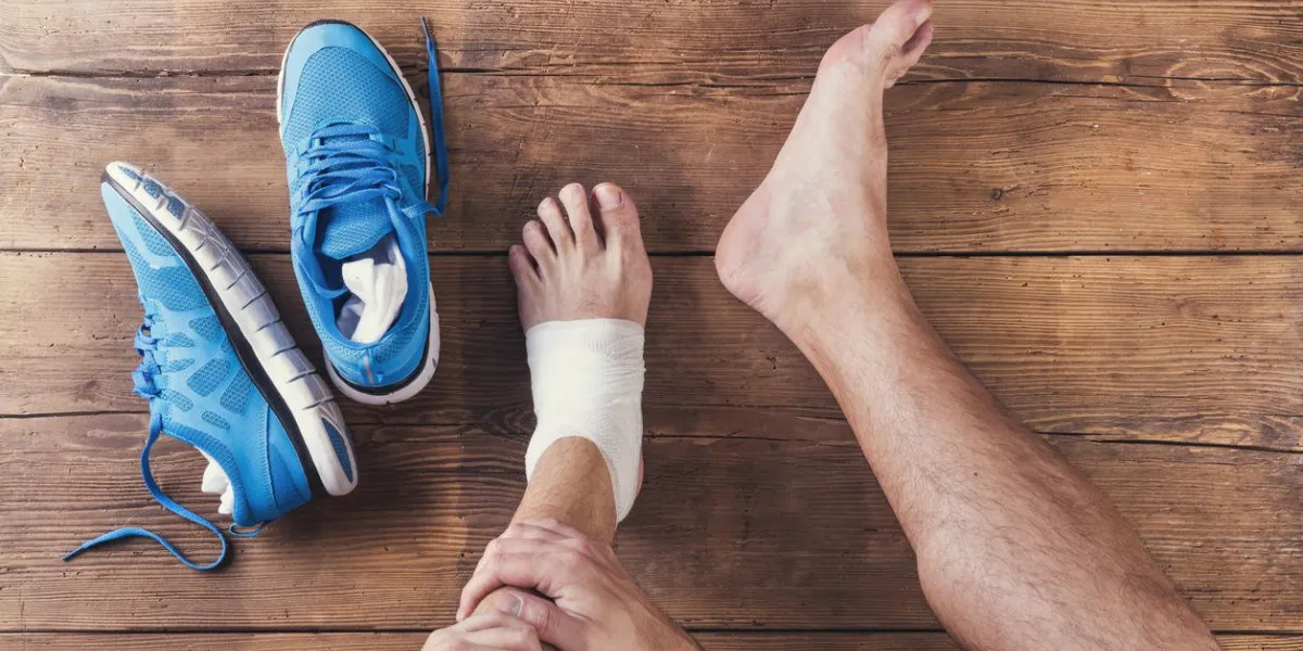 unrecognizable injured runner sitting on a wooden floor background