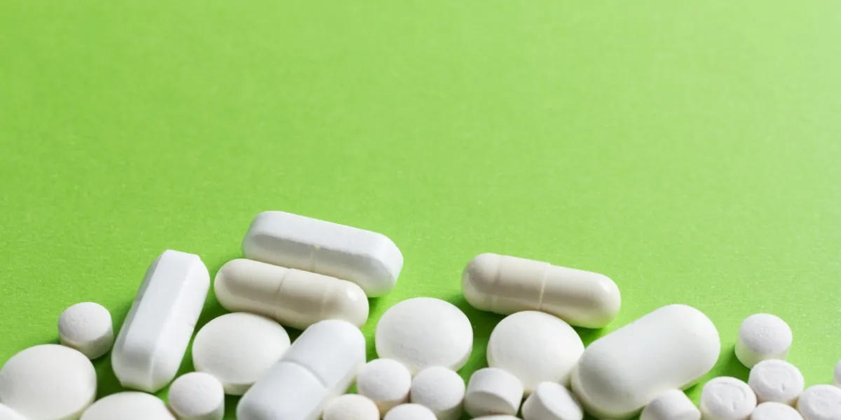 heap of white capsules on green table