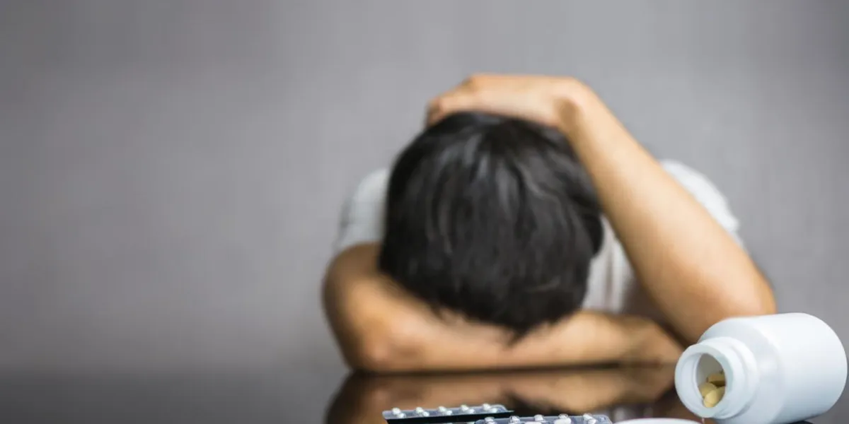 pills and medicines on table with man facing down