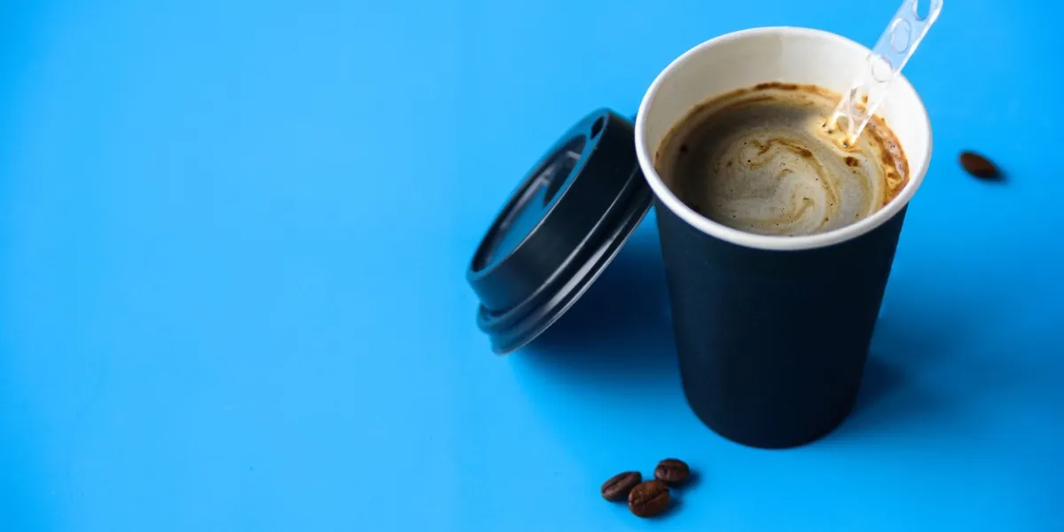 instant coffee in paper cup with cap on light blue pastel background