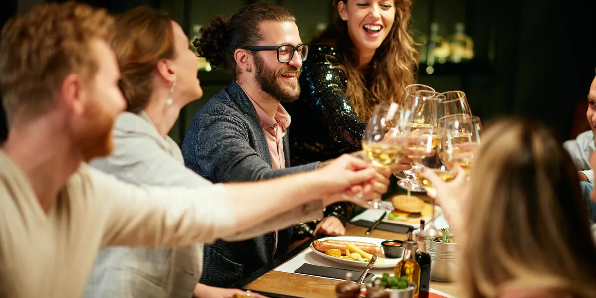 best friends sitting in restaurant for dinner and making a toast with white wine on table is food