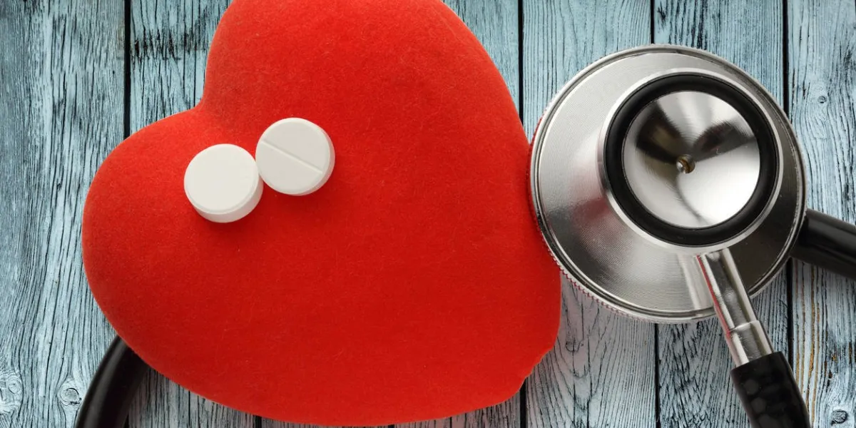coeur rouge, stéthoscope et pilules sur fond en bois