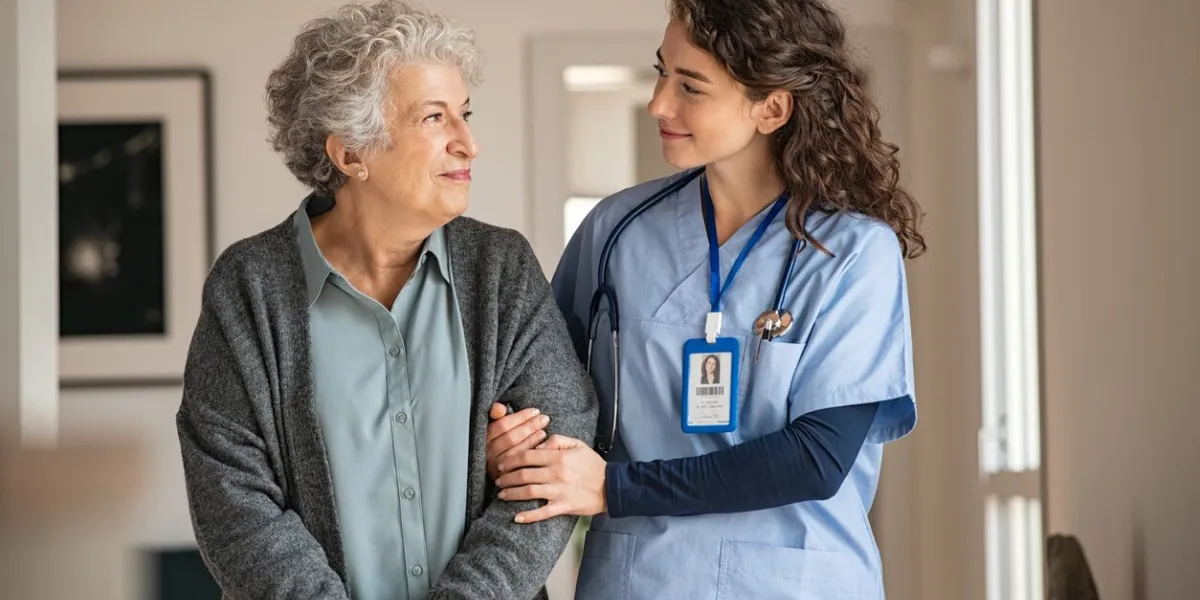 young caregiver helping senior woman walking nurse assisting her old woman patient at nursing home senior woman with walking stick being helped by nurse at home