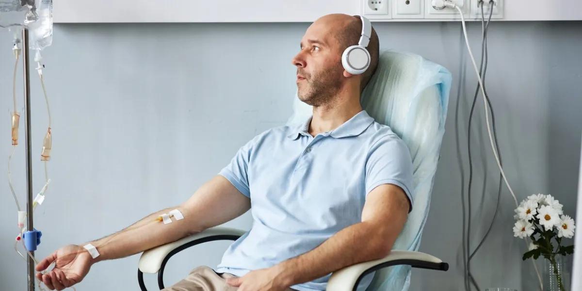 side view portrait of adult man wearing headphones and listening to music during iv drip treatment in clinic