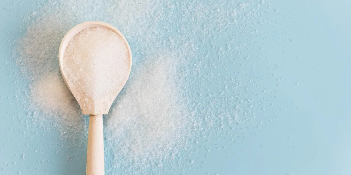 white sugar in wood spoon on wood table