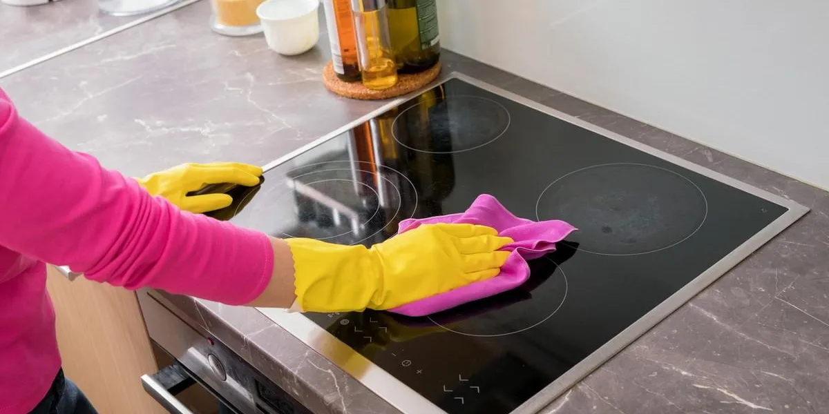 person cleaning the stove in kitchen