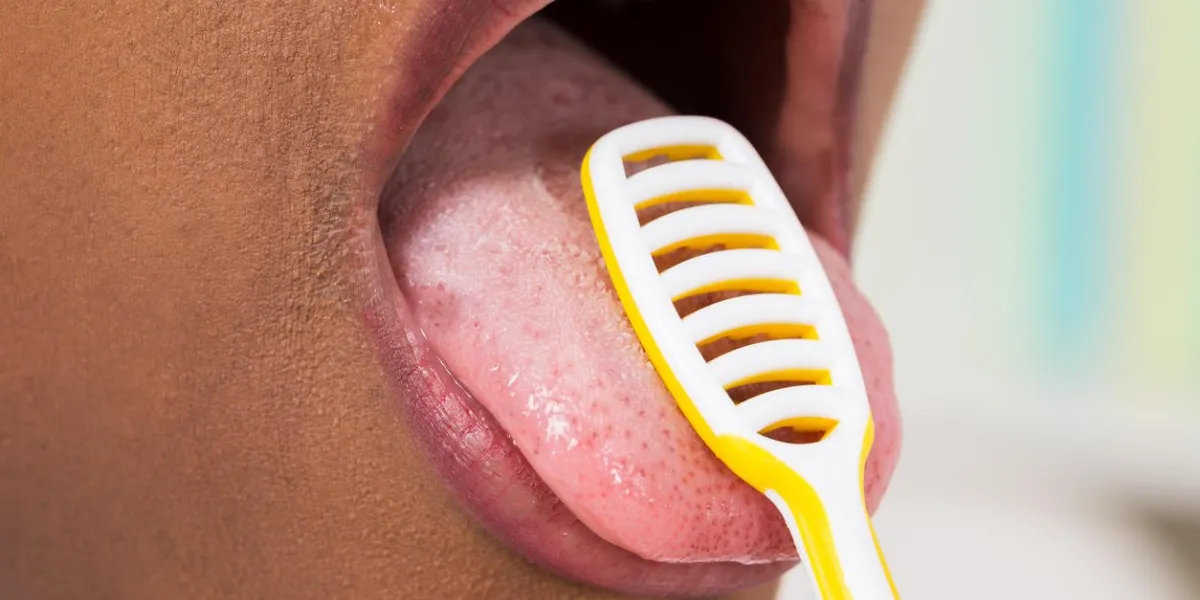close-up of young woman cleaning tongue with cleaner